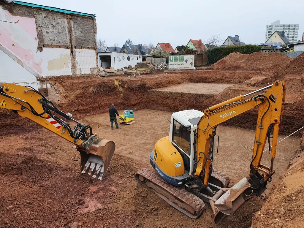 Baugrubenaushub mit Kubota-Bagger und UBW-Bauschild in Wittlich