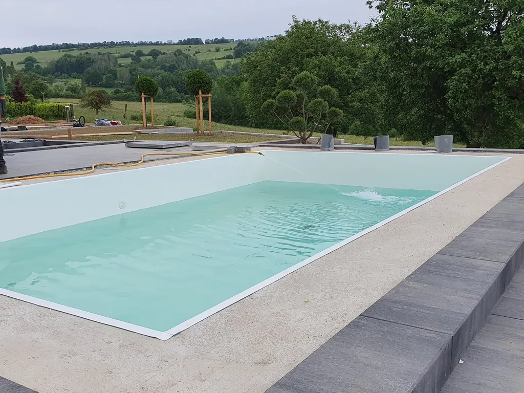 Fertiger Pool mit Wasser und Natursteinumrandung – Poolbau UBW Wittlich